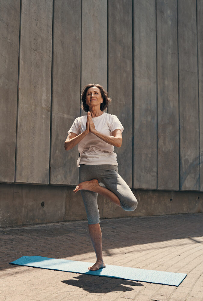 beautiful mature woman practicing yoga outdoors